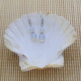 Boucles d'oreilles pendantes deux perles d'opaline blanche en verre dans sa coquille Saint-Jacques