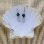 Boucles d'oreilles pendantes deux perles en pierre de lave et oeil de chat blanc dans sa coquille Saint-Jacques