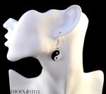 Boucles d'oreilles pendantes yin yang noires et blanches sur présentoir
